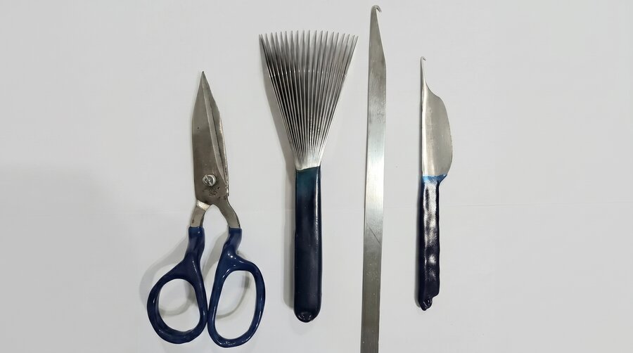 Carpet weaving tools: scissors for clipping pile, a metal comb for beating down, and a hook for knotting