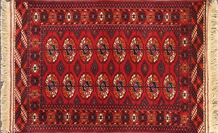 A Turkmen carpet with the classic gul medallion pattern on a deep red background