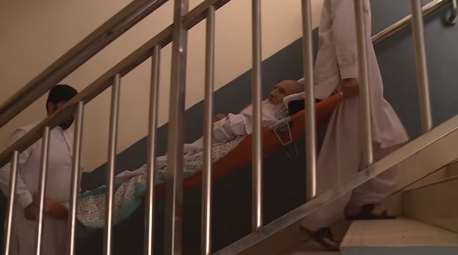 Family members carrying a patient up a hospital stairwell on a stretcher