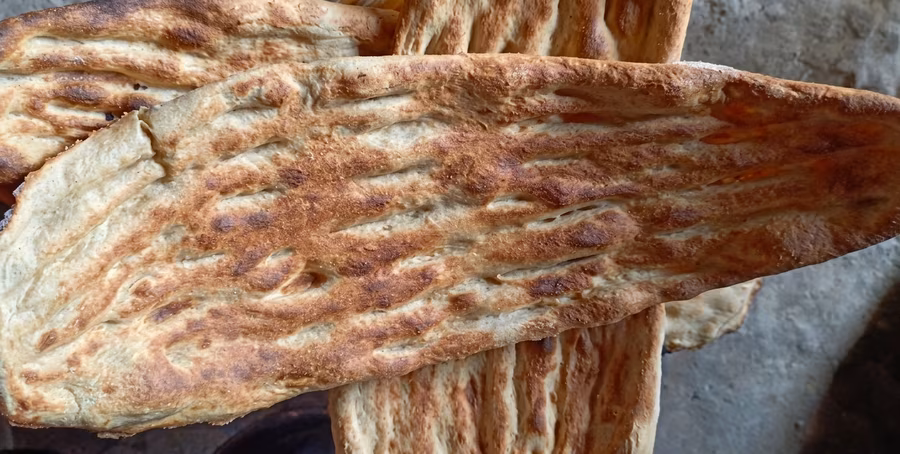 A close-up of tandoor bread, showing the ridges left by the baker's fingers