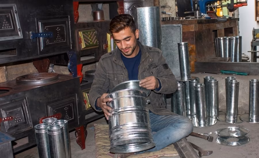 An Afghan metalworker assembling samawat parts in his workshop